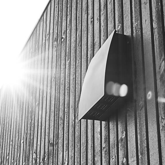 DUKA One DO 30 stormskærm i sort på afstandstykke placeret på en sort trævæg