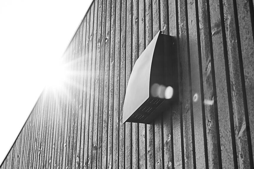 DUKA One DO 30 stormskærm i sort på afstandstykke placeret på en sort trævæg