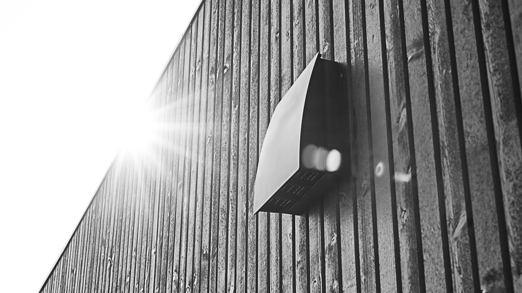 DUKA One DO 30 stormskærm i sort på afstandstykke placeret på en sort trævæg